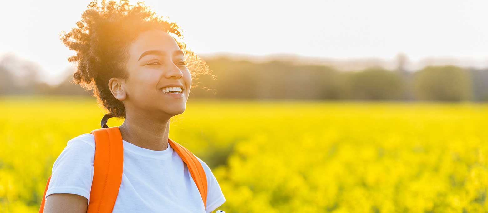 A teen girl walking in a sunny meadow